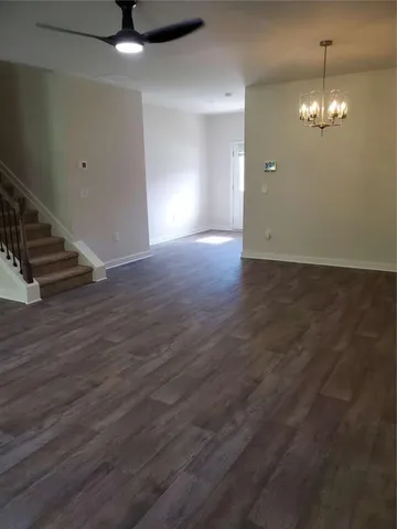 an empty room with wooden floor chandelier fan and windows