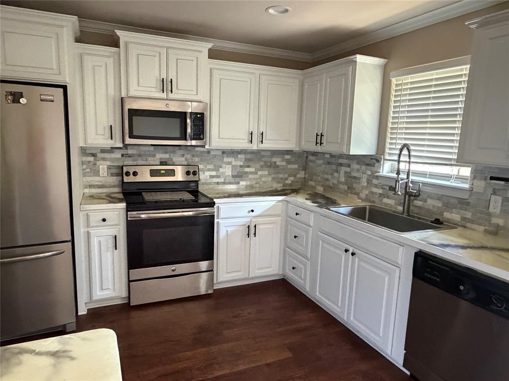 520 Big Red Circle Haughton, LA 71037 - Photo 7 of 25 Kitchen featuring white cabinetry with dark hardware, stainless steel appliances, a mosaic tile backsplash, and light-toned countertops