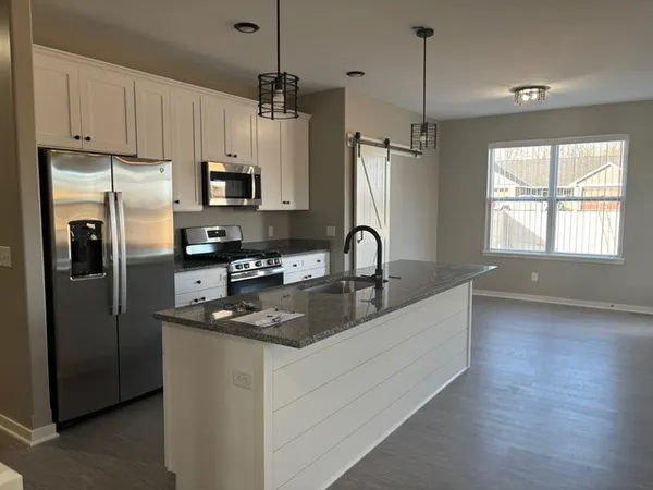 a kitchen with stainless steel appliances granite countertop a refrigerator a sink a stove a microwave and a refrigerator