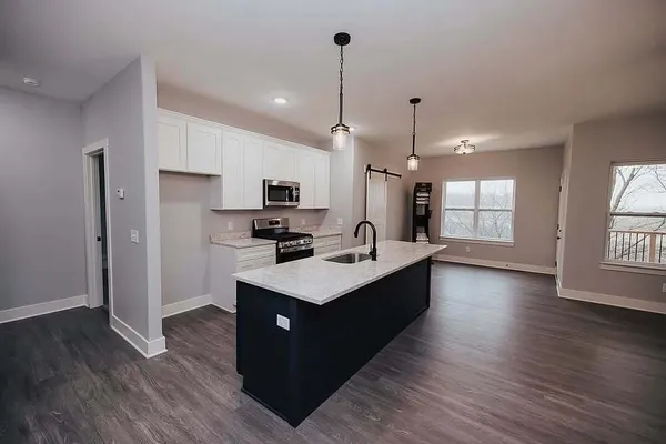 a kitchen with kitchen island granite countertop a sink appliances and wooden floor