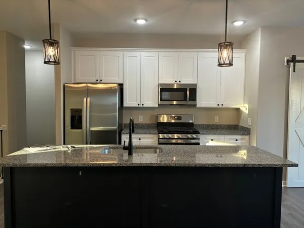 a kitchen with stainless steel appliances granite countertop a sink a stove top oven a refrigerator and a granite counter tops