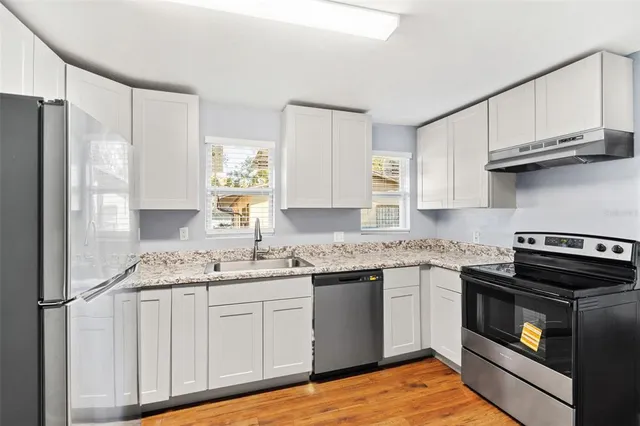 a kitchen with stainless steel appliances granite countertop a stove a sink and a refrigerator