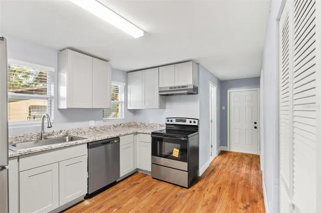 a kitchen with granite countertop a sink cabinets and stainless steel appliances