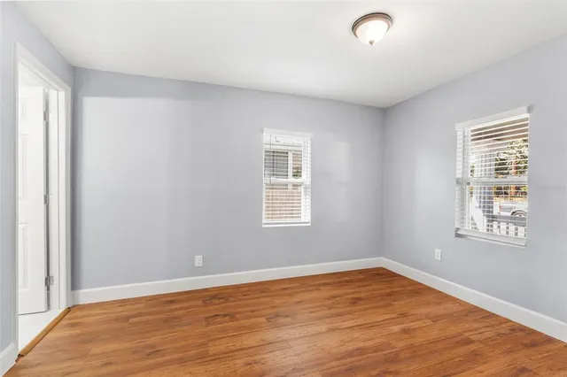 a view of an empty room with wooden floor and a window