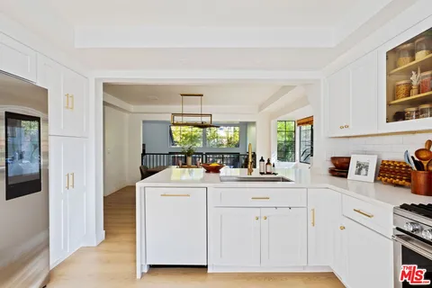 a kitchen with white cabinets and sink