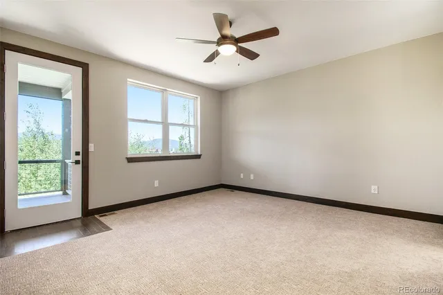 an empty room with windows and ceiling fan