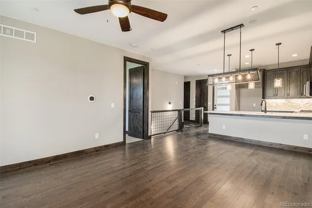 an empty room with wooden floor kitchen view and windows