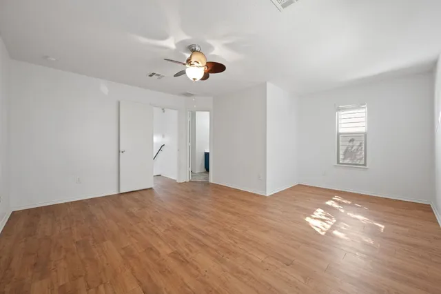 a view of an empty room with window and wooden floor