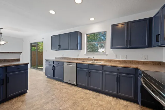 a kitchen with stainless steel appliances granite countertop wooden cabinets a stove top oven a sink and dishwasher