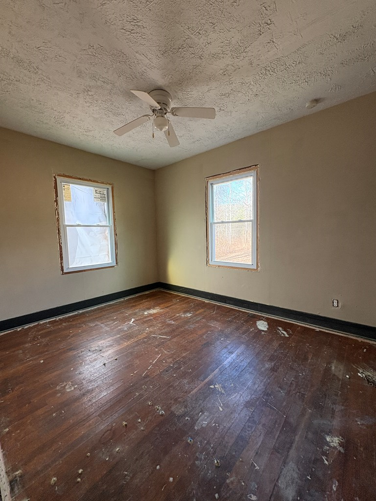 62 Pleasant Hill Road Murphy, NC 28906 - Photo 19 of 28 an empty room with wooden floor chandelier fan and windows
