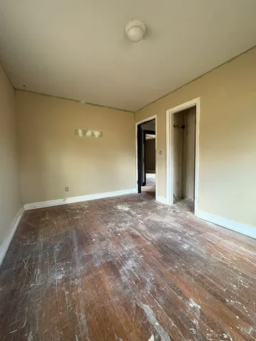 a view of an empty room with window and wooden floor