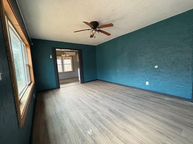 a view of an empty room with a window and wooden floor