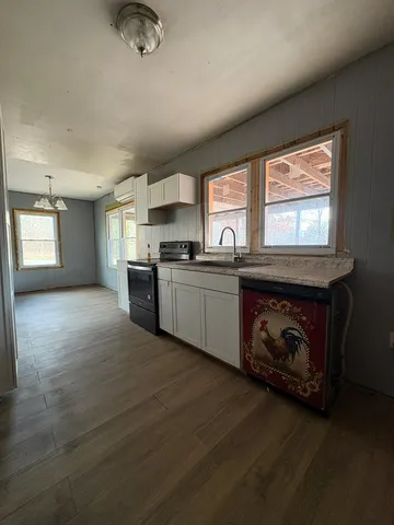 a kitchen with stainless steel appliances granite countertop a sink a stove cabinets and a window
