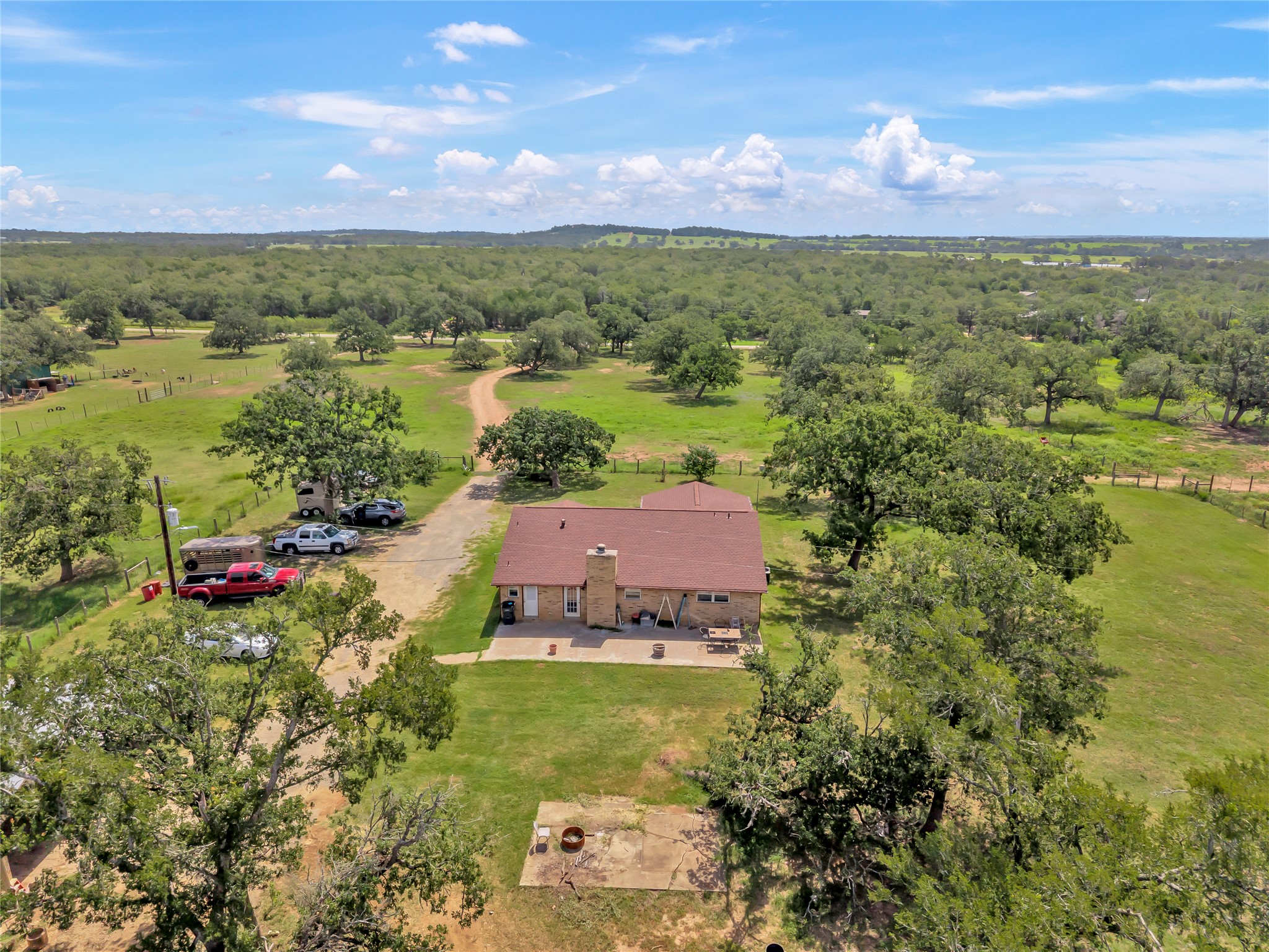 1080 League Line Road Paige, TX 78659 - Photo 35 of 39 A metal-roofed home sits nestled within rolling pastures and mature shade trees.