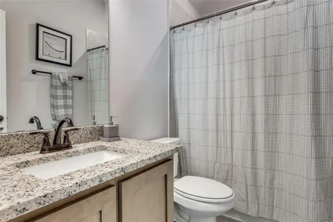 a bathroom with a granite countertop sink a toilet and a mirror