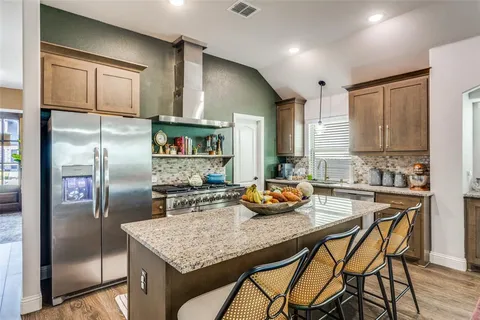 a kitchen with stainless steel appliances granite countertop a refrigerator a sink a stove and island
