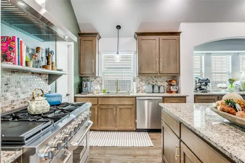 a kitchen with stainless steel appliances granite countertop a stove a sink dishwasher and cabinets with wooden floor