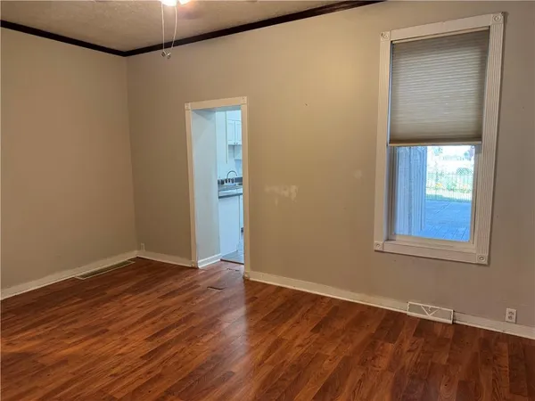 a view of an empty room with wooden floor and a window