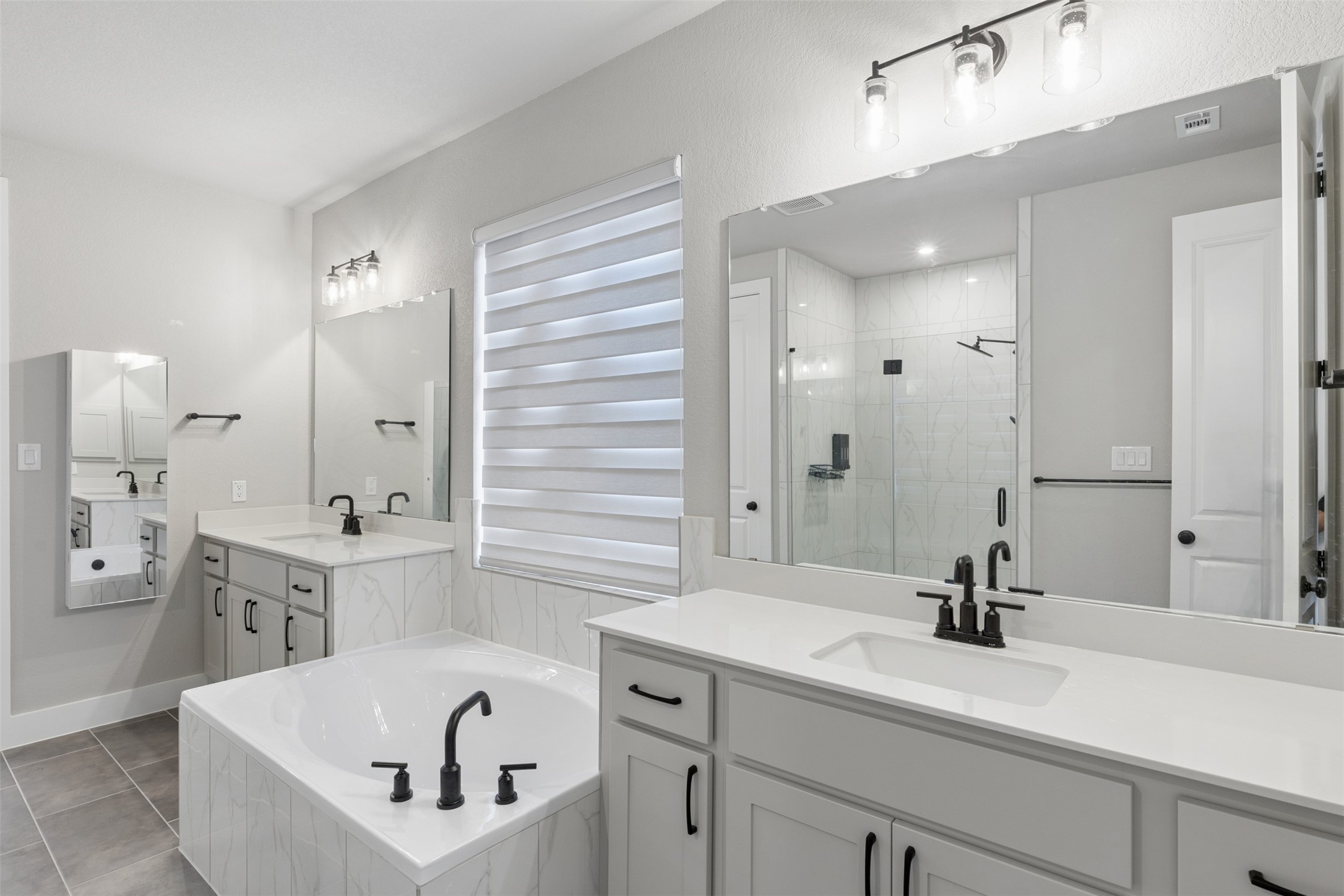 1508 Cardinal Lane Round Rock, TX 78681 - Photo 21 of 35 Bathroom with two vanities, a shower stall, a bath, and light tile patterned flooring