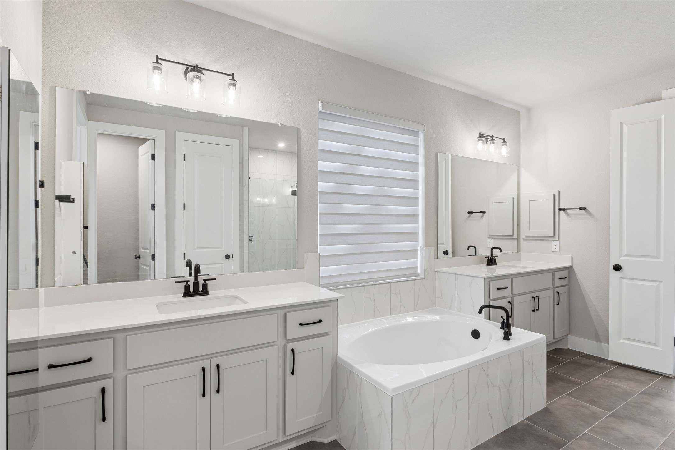 1508 Cardinal Lane Round Rock, TX 78681 - Photo 22 of 35 Full bath featuring two vanities, a garden tub, dark tile patterned flooring, and walk in shower