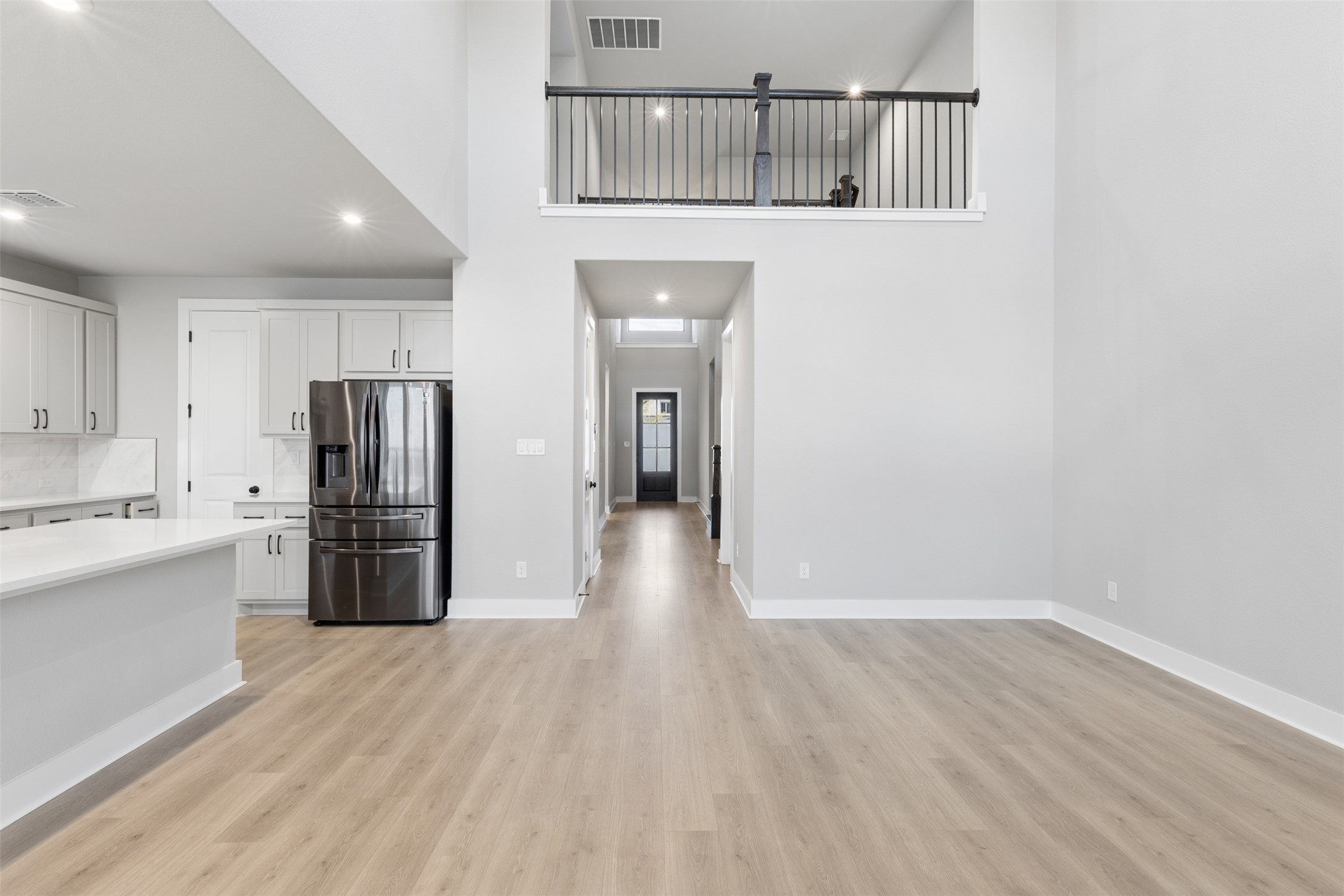 1508 Cardinal Lane Round Rock, TX 78681 - Photo 5 of 35 Kitchen featuring stainless steel refrigerator with ice dispenser, a high ceiling, white cabinets, recessed lighting, and light wood-style floors