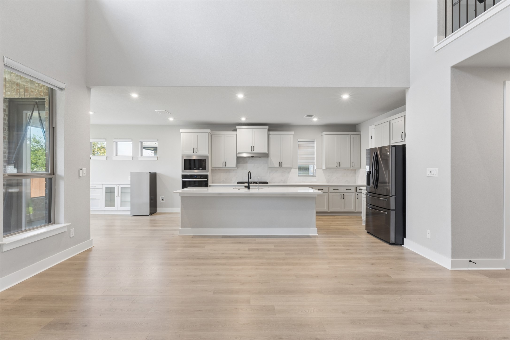 1508 Cardinal Lane Round Rock, TX 78681 - Photo 6 of 35 Kitchen featuring stainless steel appliances, a kitchen island with sink, white cabinetry, decorative backsplash, and light wood-type flooring