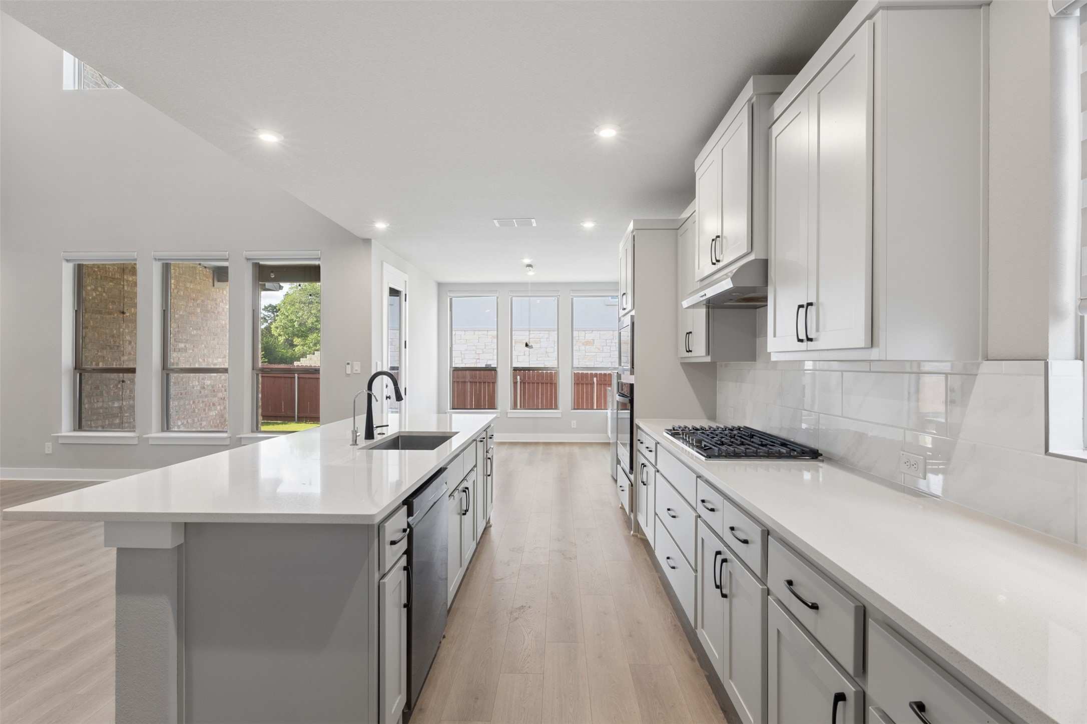 1508 Cardinal Lane Round Rock, TX 78681 - Photo 7 of 35 Kitchen with light wood-style floors, a large island with sink, backsplash, recessed lighting, and light stone countertops