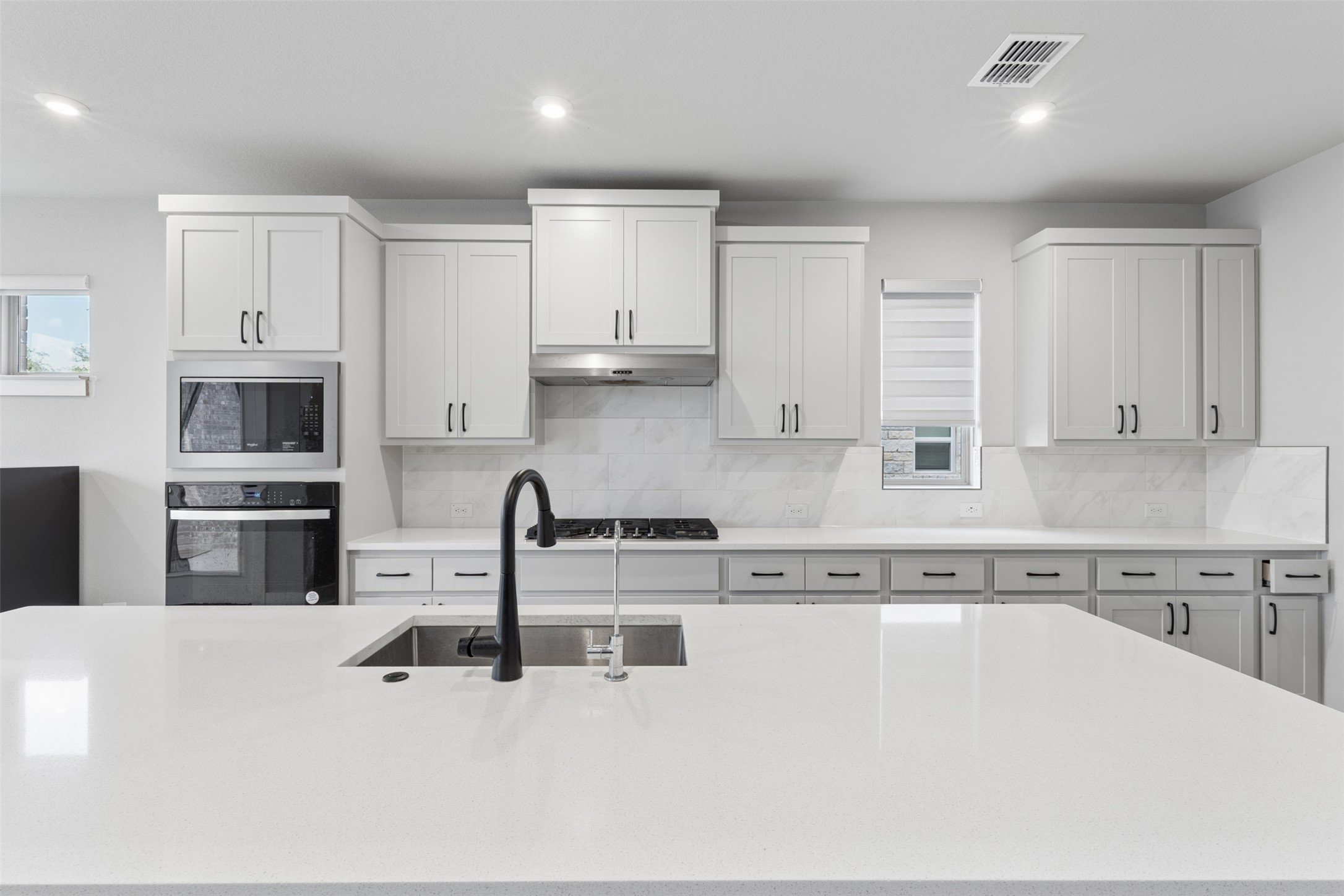 1508 Cardinal Lane Round Rock, TX 78681 - Photo 8 of 35 Kitchen featuring black oven, light stone counters, tasteful backsplash, stainless steel microwave, and recessed lighting