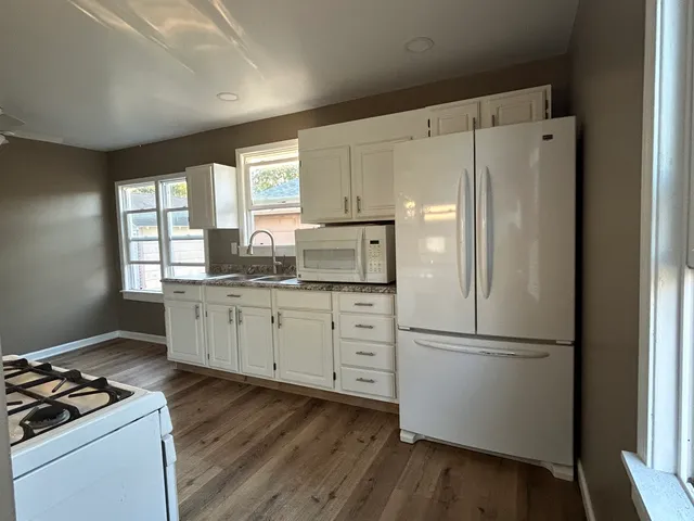 a kitchen with white cabinets white stainless steel appliances and window