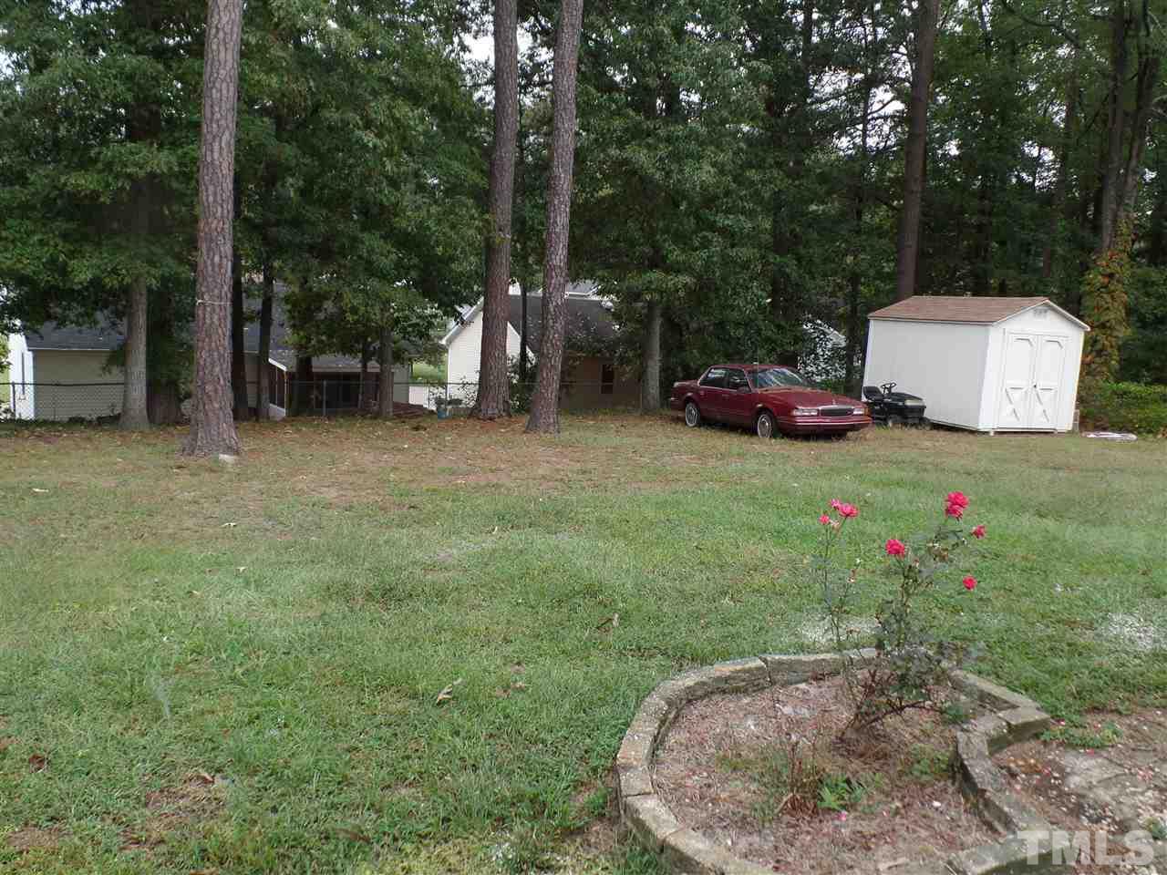 712 Cooper Road Raleigh, NC 27610 - Photo 8 of 12 a view of a backyard with table and chairs and a small cabin