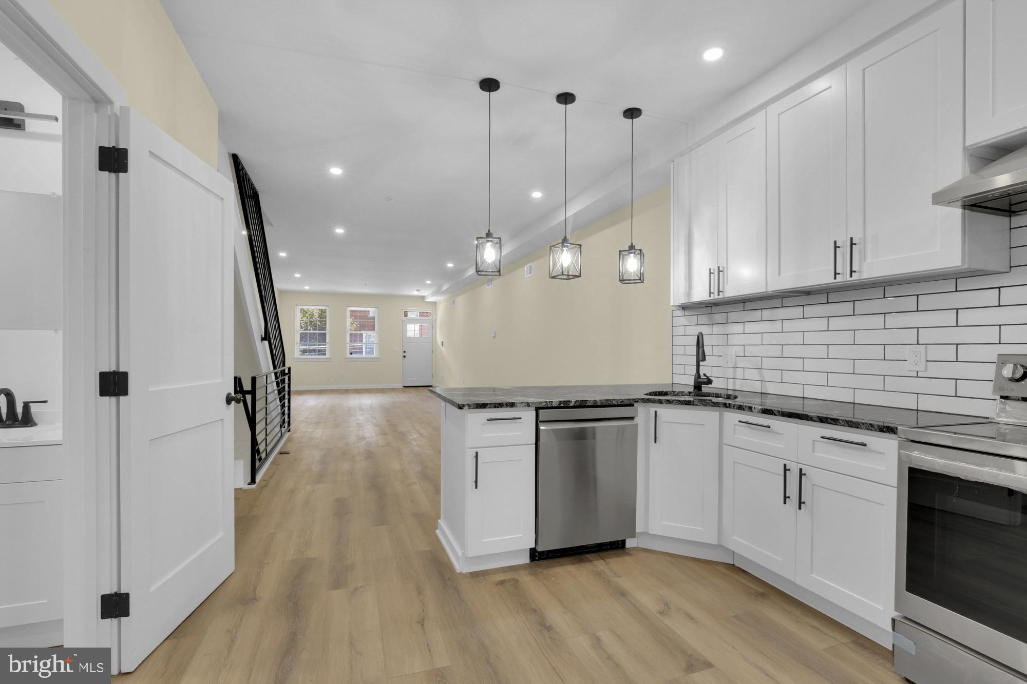 2670 Braddock Street Philadelphia, PA 19125 - Photo 4 of 47 a kitchen with granite countertop a stove a sink a refrigerator and white cabinets with wooden floor