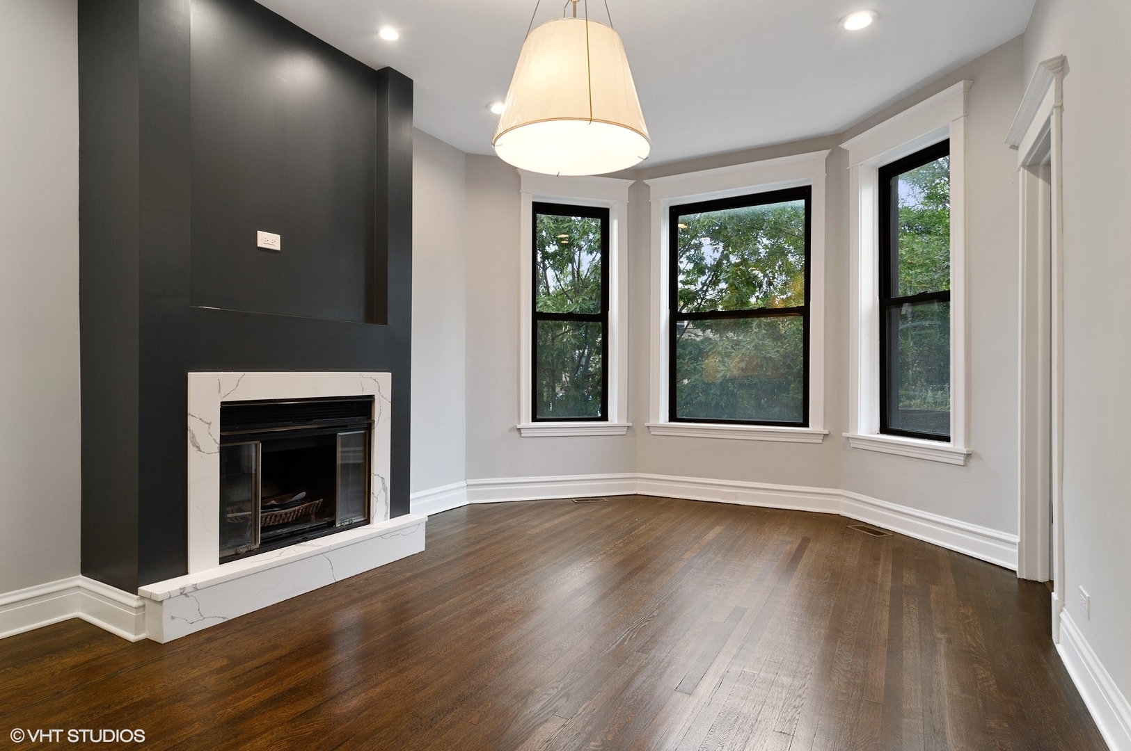 1211 West Addison Street, Unit 2 Chicago, IL 60613 - Photo 2 of 16 a view of an empty room with wooden floor fireplace and a window