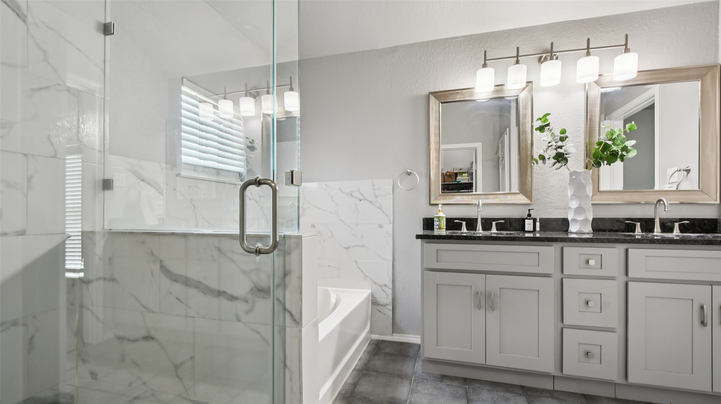 13131 Crane Road Buda, TX 78610 - Photo 15 of 18 a bathroom with a double vanity sink a mirror a bathtub and next to a window