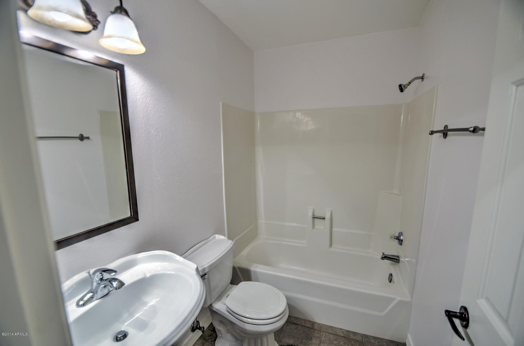 4211 East Carson Road Phoenix, AZ 85042 - Photo 1 of 19 a white toilet sitting next to a bathroom sink and a shower