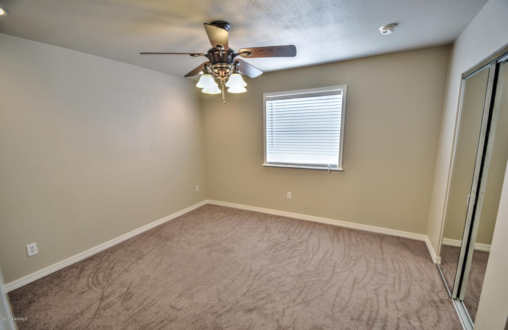 4211 East Carson Road Phoenix, AZ 85042 - Photo 2 of 19 an empty room with a chandelier fan and windows