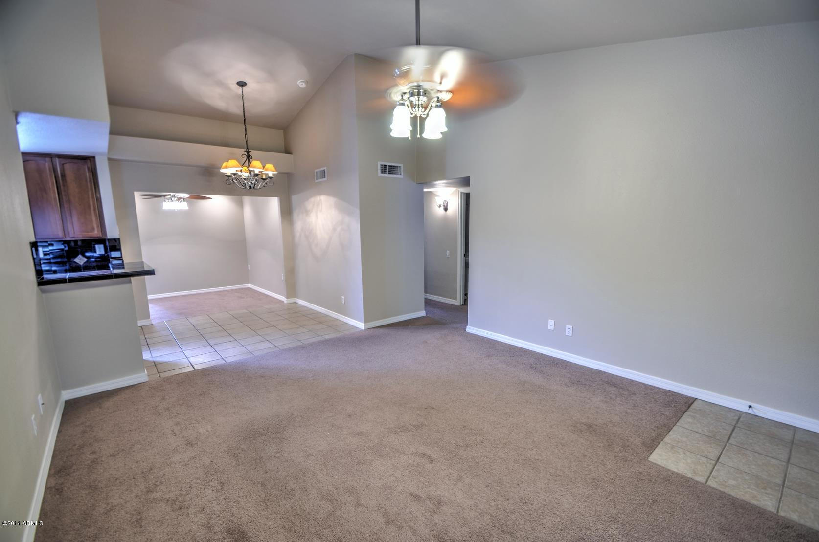4211 East Carson Road Phoenix, AZ 85042 - Photo 6 of 19 an empty room with kitchen view and wooden floor
