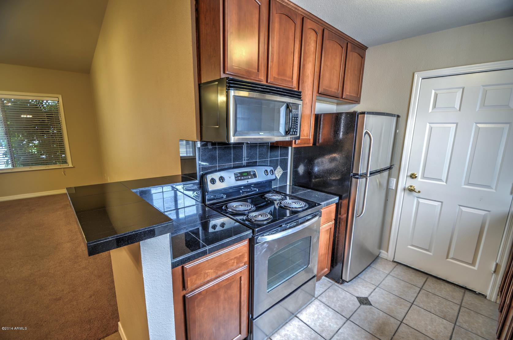 4211 East Carson Road Phoenix, AZ 85042 - Photo 9 of 19 a kitchen with stainless steel appliances granite countertop a refrigerator stove top oven and sink