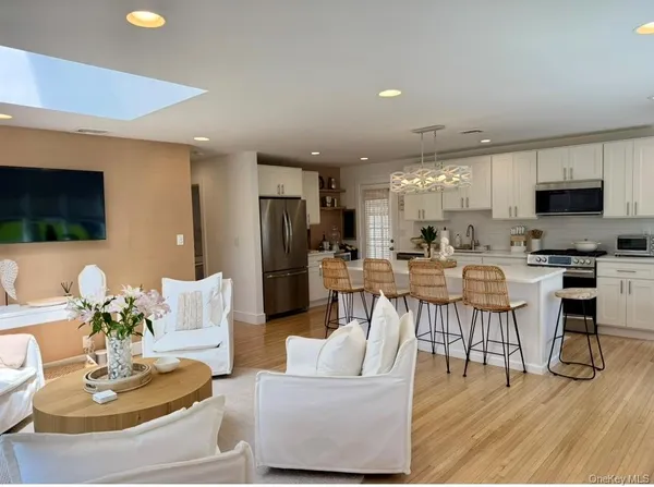 a living room with stainless steel appliances kitchen island granite countertop a dining table chairs and a kitchen view