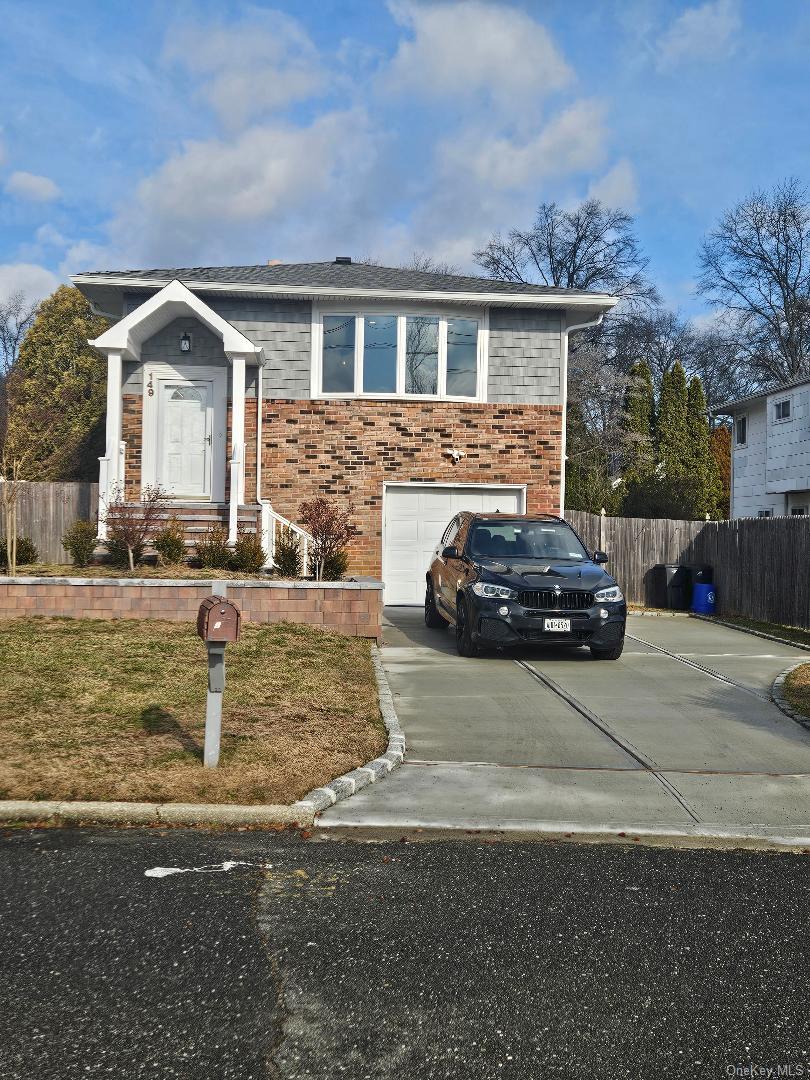 149 Truxton Road Dix Hills, NY 11746 - Photo 1 of 22 View of front of house featuring concrete driveway, a garage, and brick siding