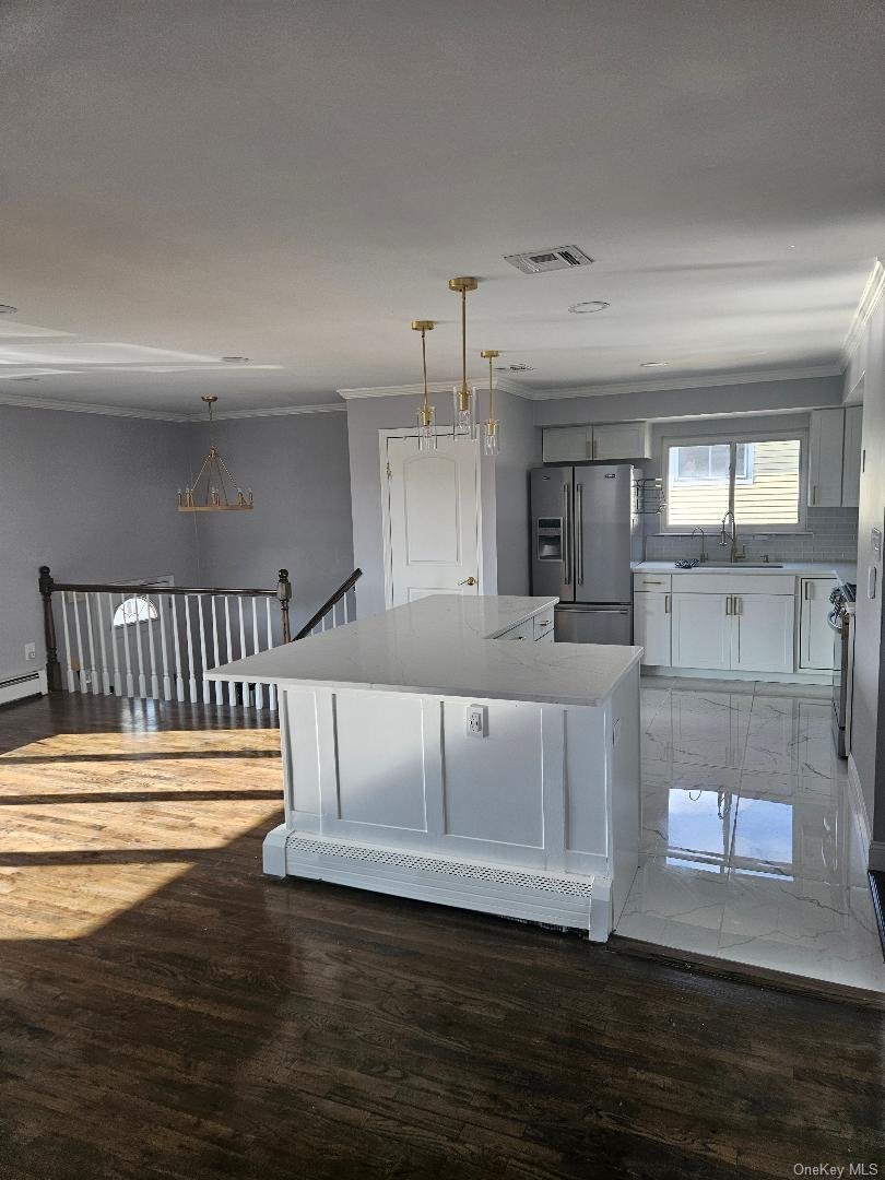 149 Truxton Road Dix Hills, NY 11746 - Photo 12 of 22 Kitchen with crown molding, appliances with stainless steel finishes, hanging light fixtures, a center island, and decorative backsplash