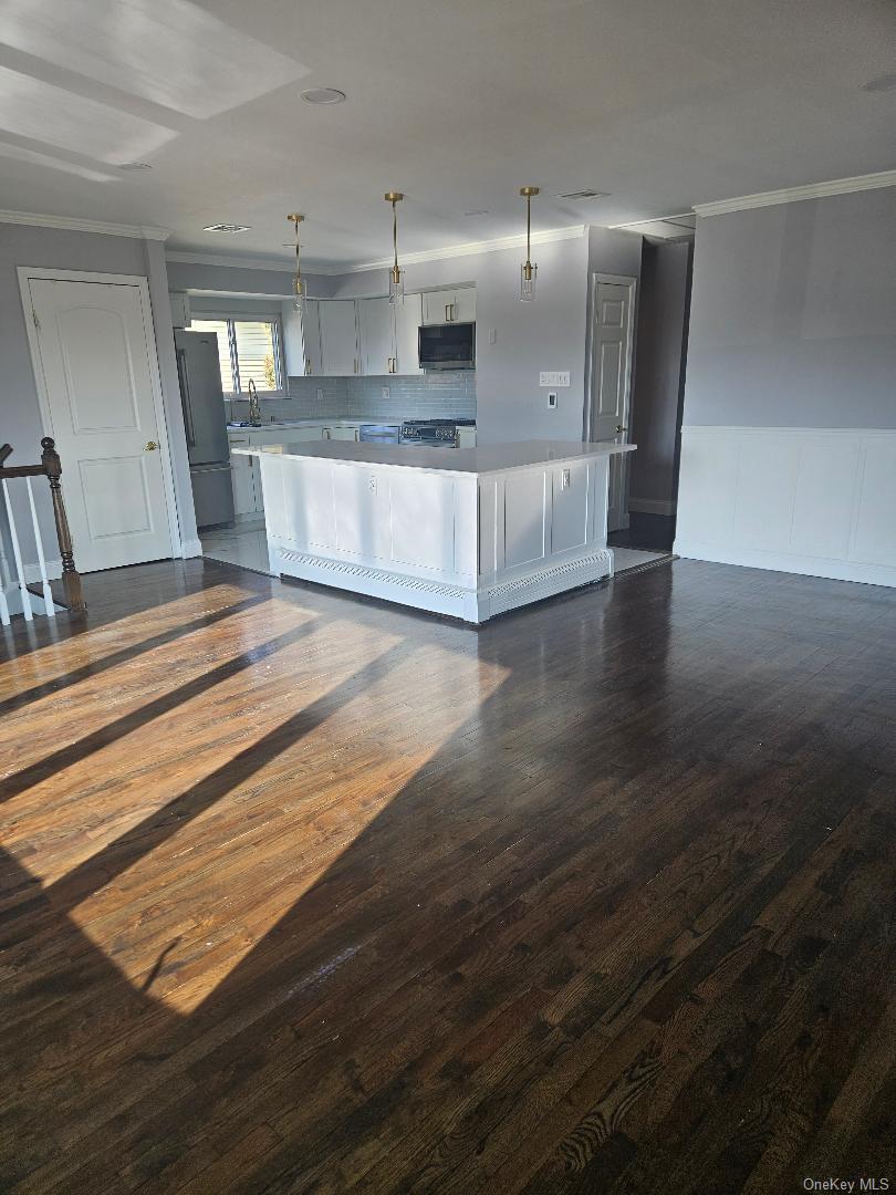 149 Truxton Road Dix Hills, NY 11746 - Photo 13 of 22 Kitchen with white cabinetry, ornamental molding, pendant lighting, a center island, and dark wood-style floors