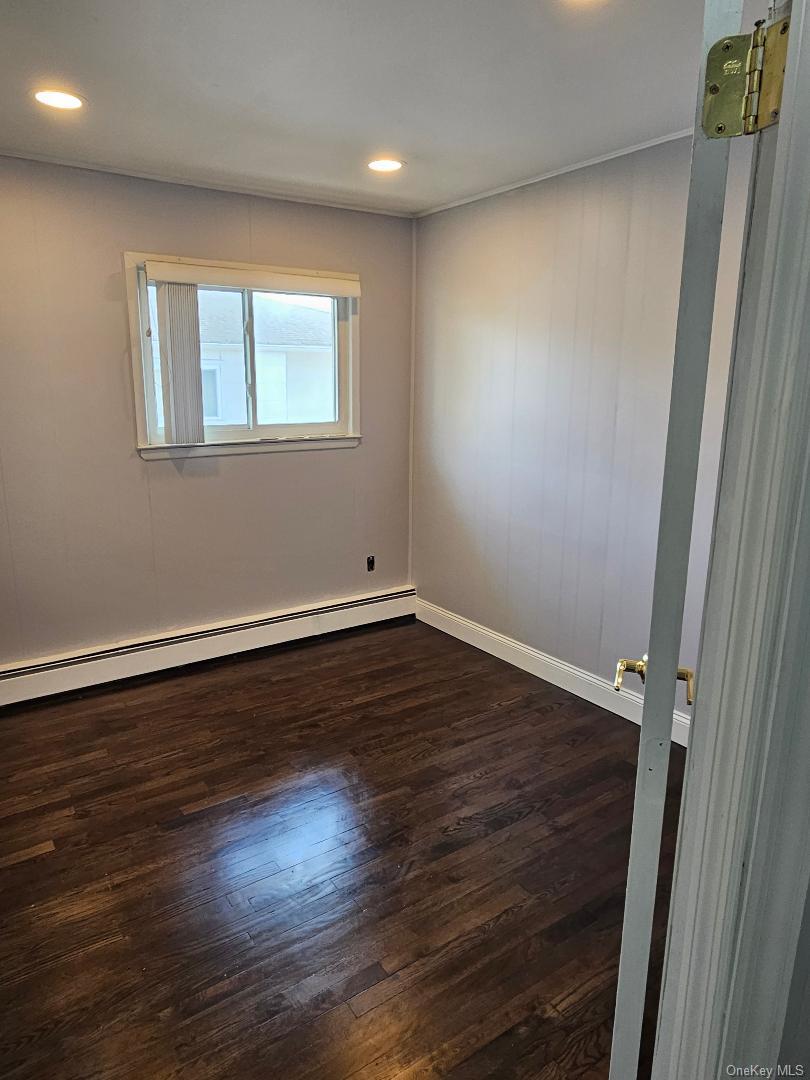 149 Truxton Road Dix Hills, NY 11746 - Photo 15 of 22 Spare room featuring baseboard heating, dark wood-style flooring, and recessed lighting