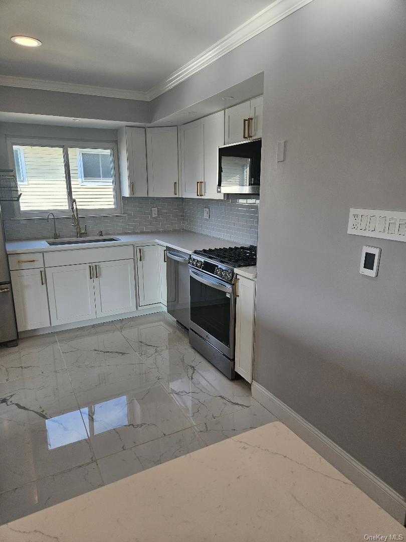 149 Truxton Road Dix Hills, NY 11746 - Photo 21 of 22 Kitchen with white cabinets, stainless steel appliances, crown molding, and light marble finish flooring