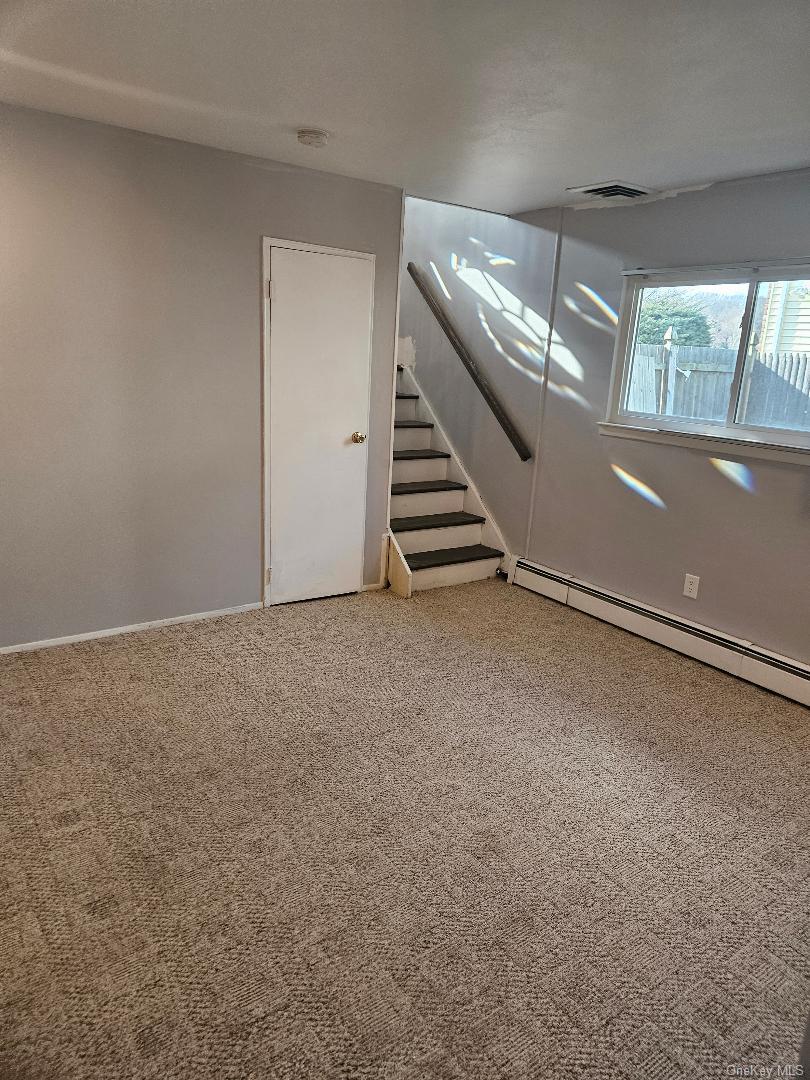 149 Truxton Road Dix Hills, NY 11746 - Photo 6 of 22 Basement featuring baseboard heating, light colored carpet, and stairs