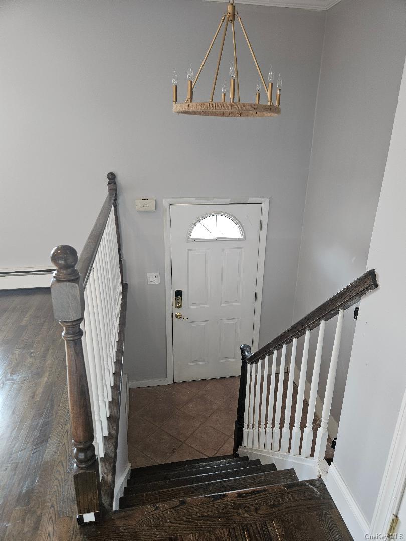 149 Truxton Road Dix Hills, NY 11746 - Photo 8 of 22 Foyer featuring stairway, dark tile patterned flooring, and a chandelier
