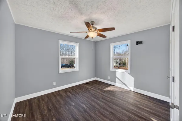 a view of an empty room with window and wooden floor