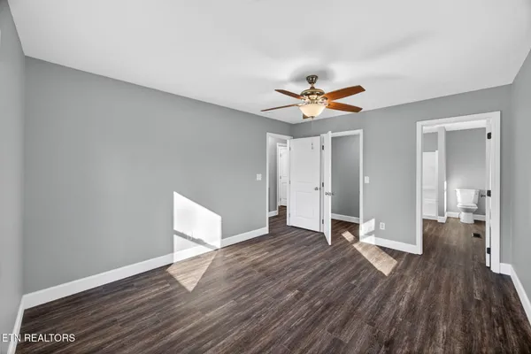 an empty room with wooden floor and a ceiling fan