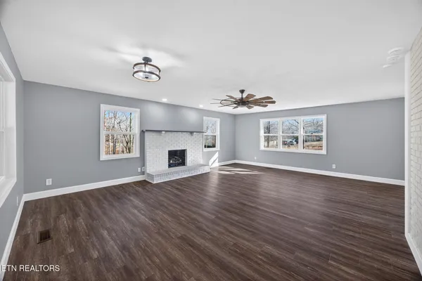 an empty room with windows and fireplace