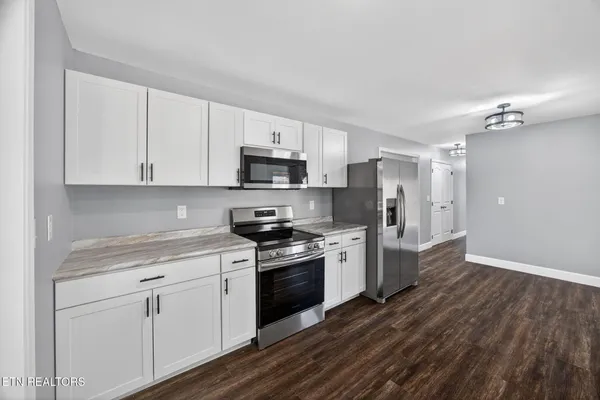 a kitchen with stainless steel appliances white cabinets a sink a stove a refrigerator and white cabinets