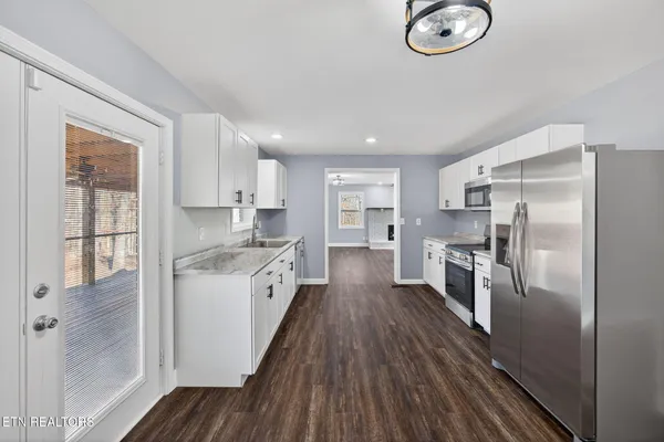 a large kitchen with a center island wooden floor stainless steel appliances and windows